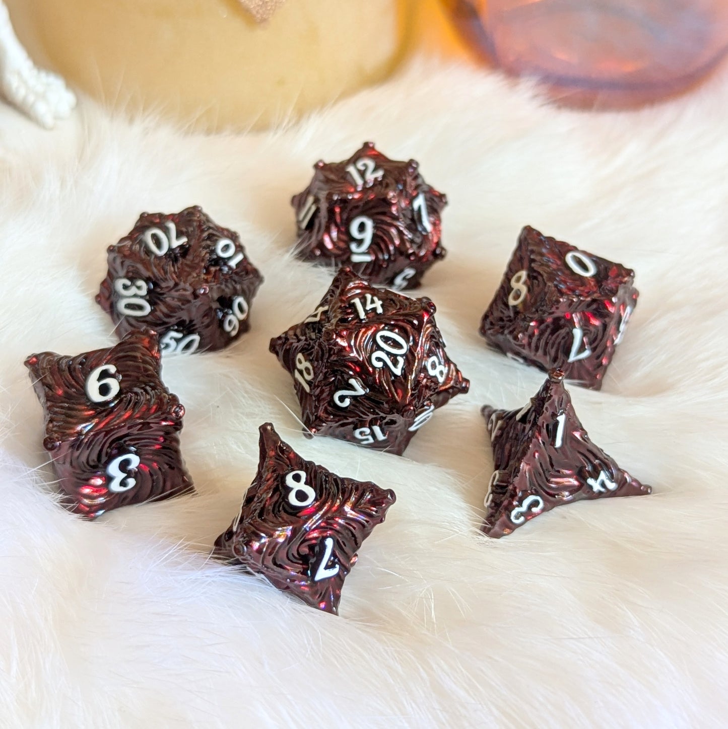 Deep red enchanted bark metal dice set with white numbers on a soft, furry surface, perfect for thrilling tabletop adventures.