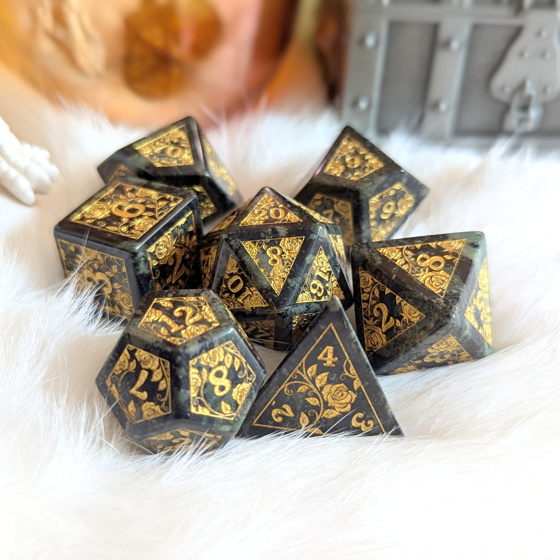 Kambaba Jasper Rose Dice Set with gold-engraved rose vines on white fur background.