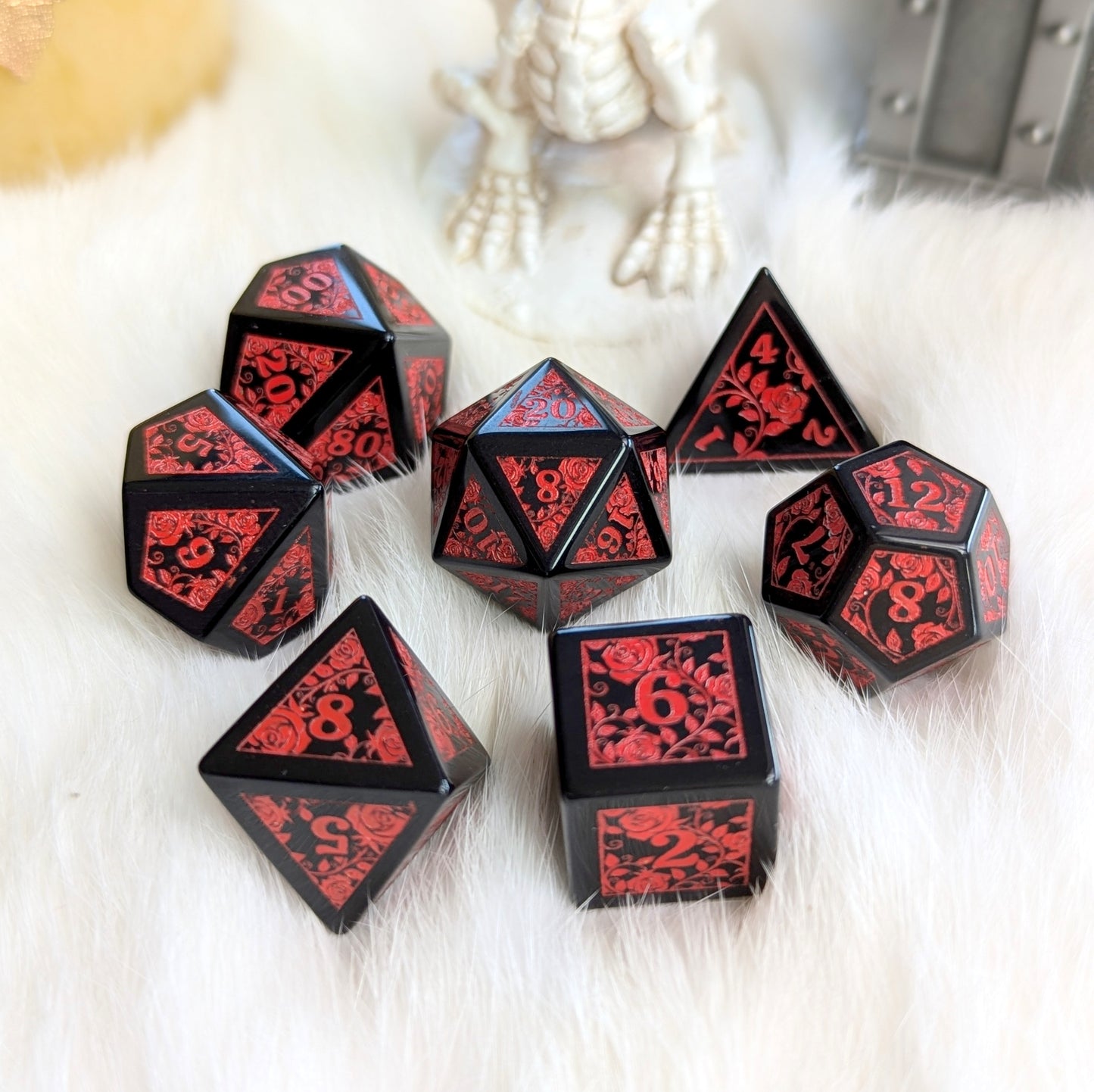 Obsidian Rose Vine Gemstone Dice Set with red rose vine engravings on a white fur background, showcasing elegance and intensity.