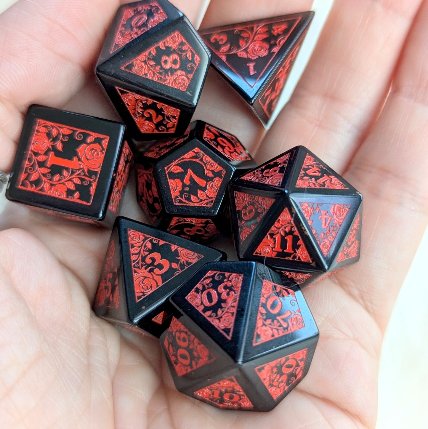 Obsidian Rose Vine Gemstone Dice Set with red vine engravings held in hand.