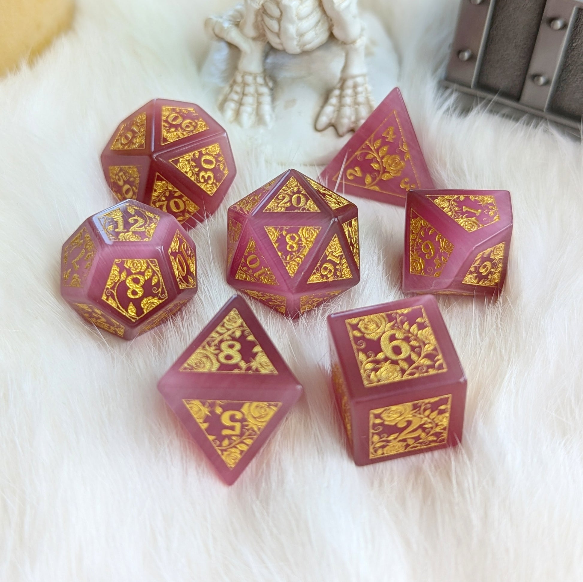 Rose Cat’s Eye Rose Vine Glass Dice Set with gold engraved floral designs on soft pink dice, elegantly displayed on plush fabric.