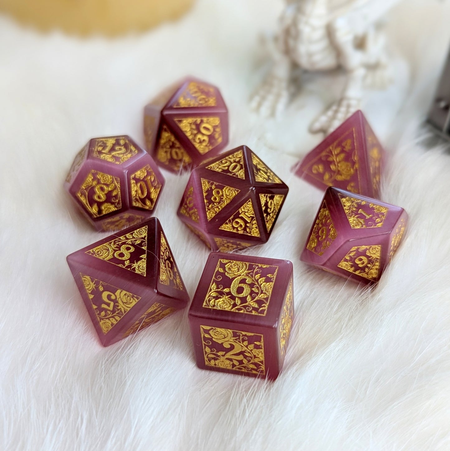 Rose Cat's Eye Rose Vine Glass Dice Set with gold engraved vine designs on a soft surface.