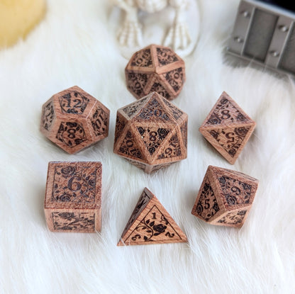 Rosewood dice set with engraved rose vine design on white fur background.