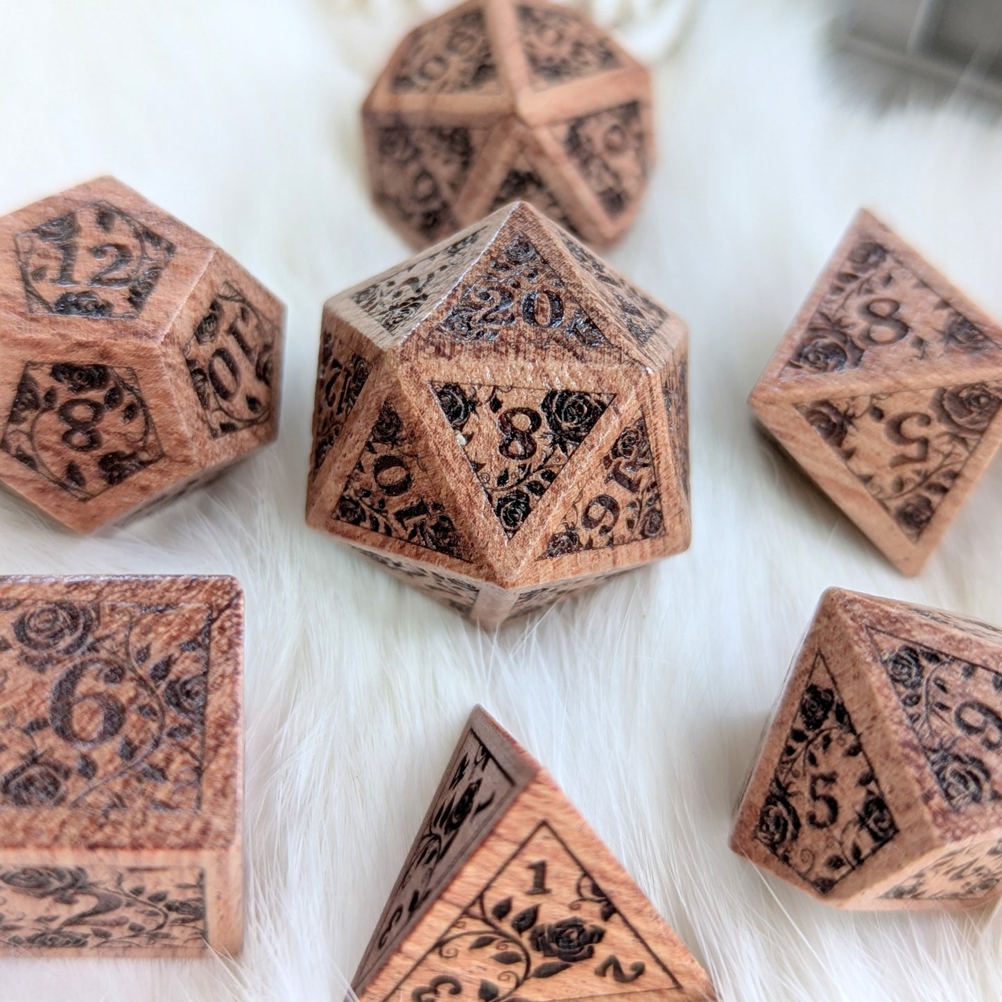 Rosewood Rose Vine Engraved Dice Set on a fluffy white surface, showcasing intricate vine and blossom designs on each die.