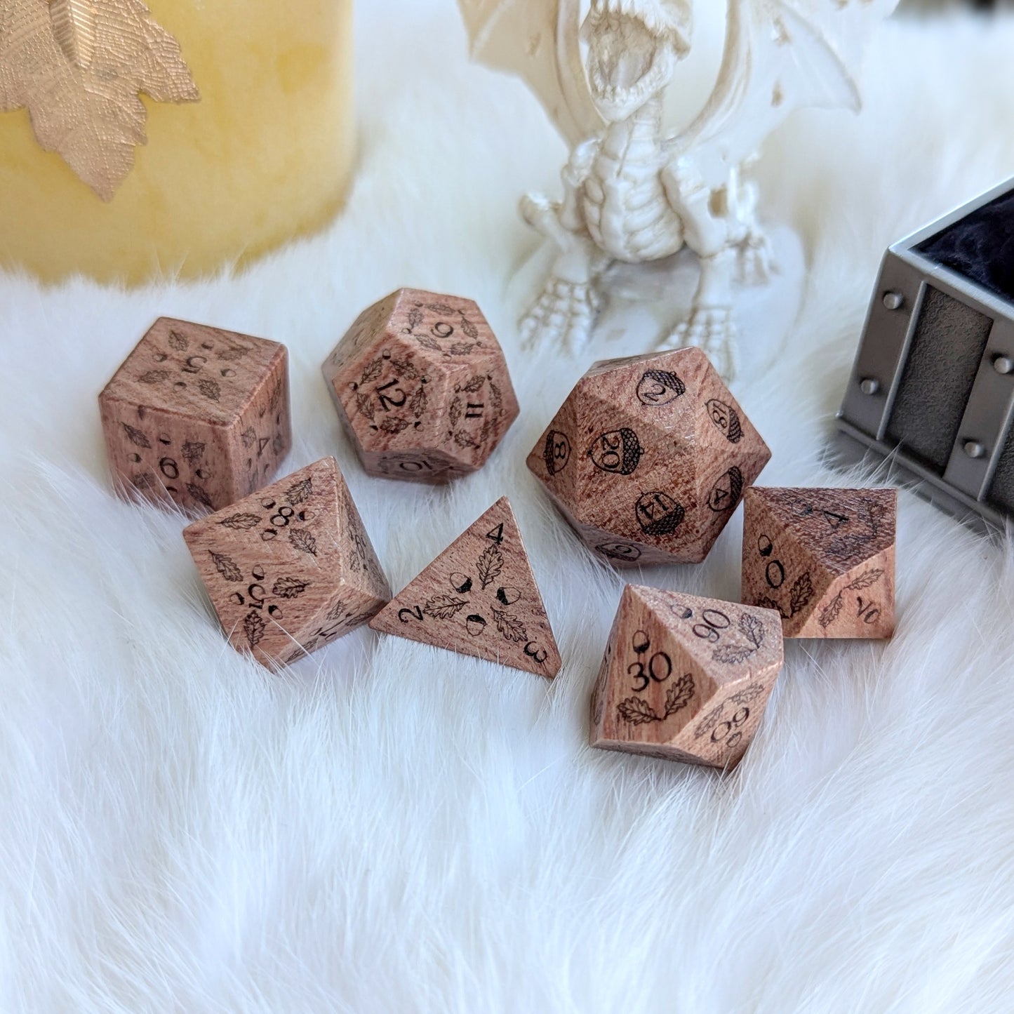 Oak Grove Engraved Rosewood Dice Set with intricate acorn and oak leaf engravings on a fluffy white surface.