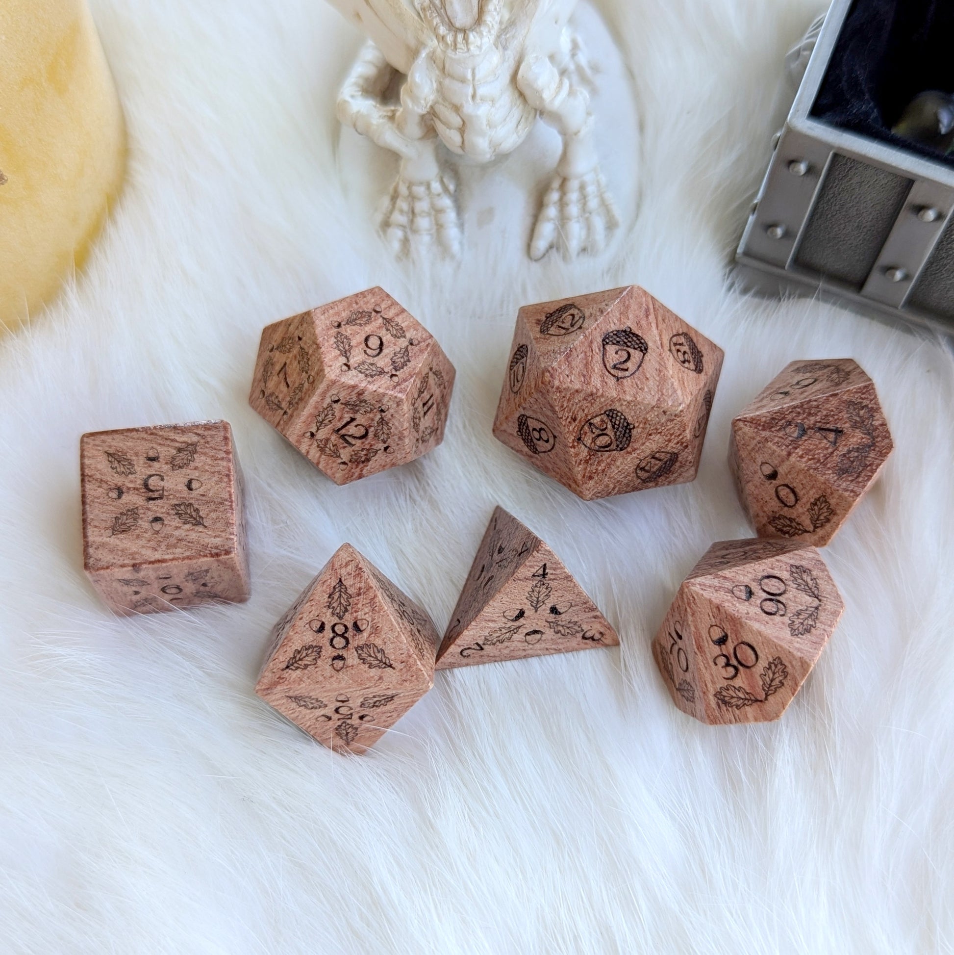 Oak Grove Engraved Rosewood Dice Set with acorn and oak leaf engravings on fluffy white surface.