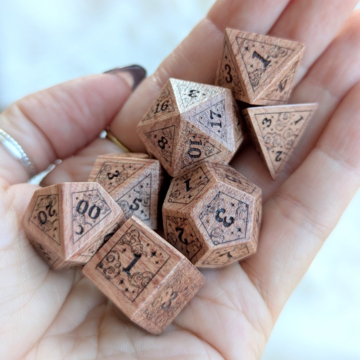 Hand holding Dreamy Rosewood Engraved Dice Set with ethereal cloud and star engravings, showcasing warm-toned wooden dice.