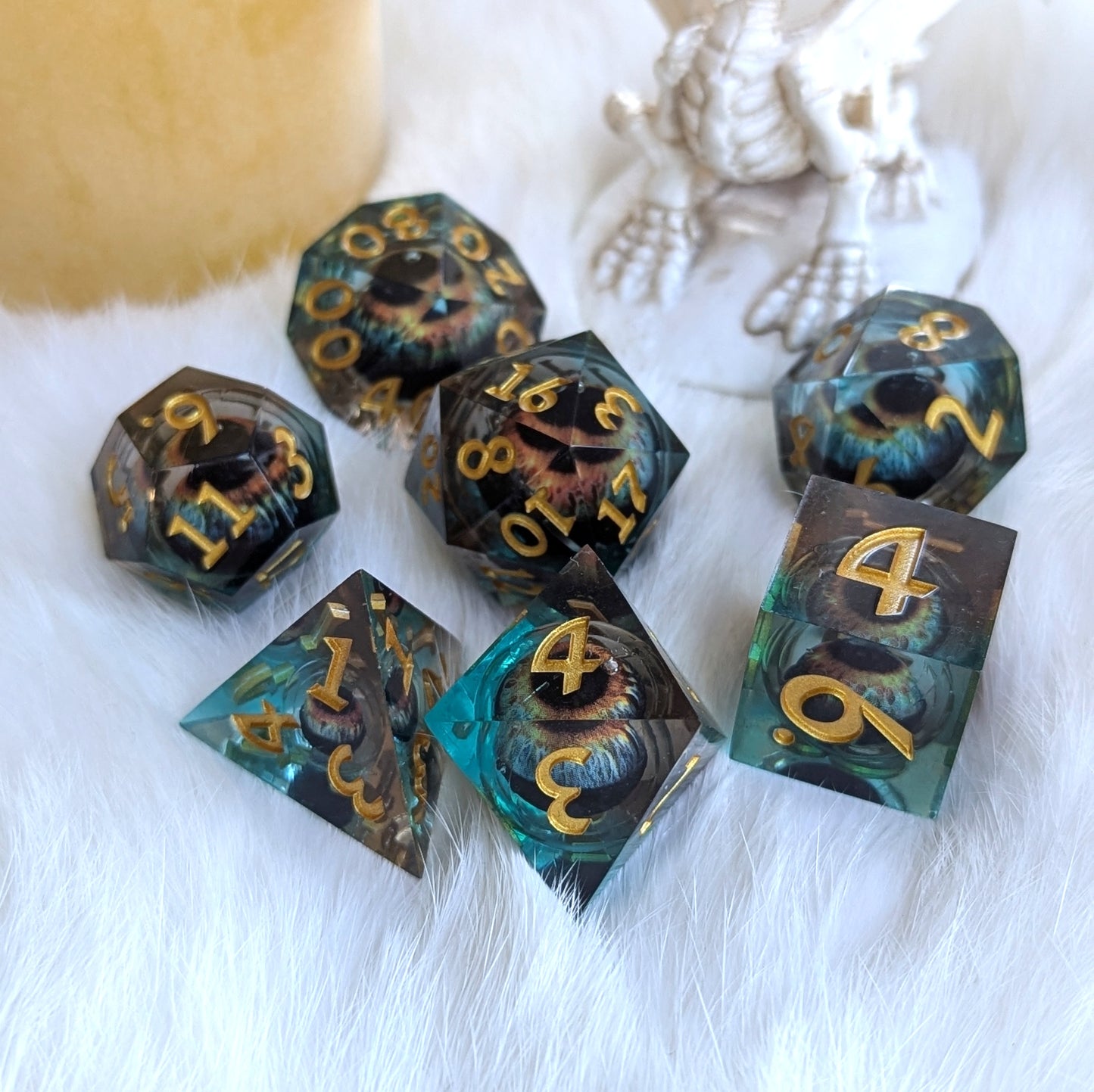 Watcher’s Gaze Liquid Core Dice Set with mystical eye design, sharp edges, and gold numbering on a white fur background.