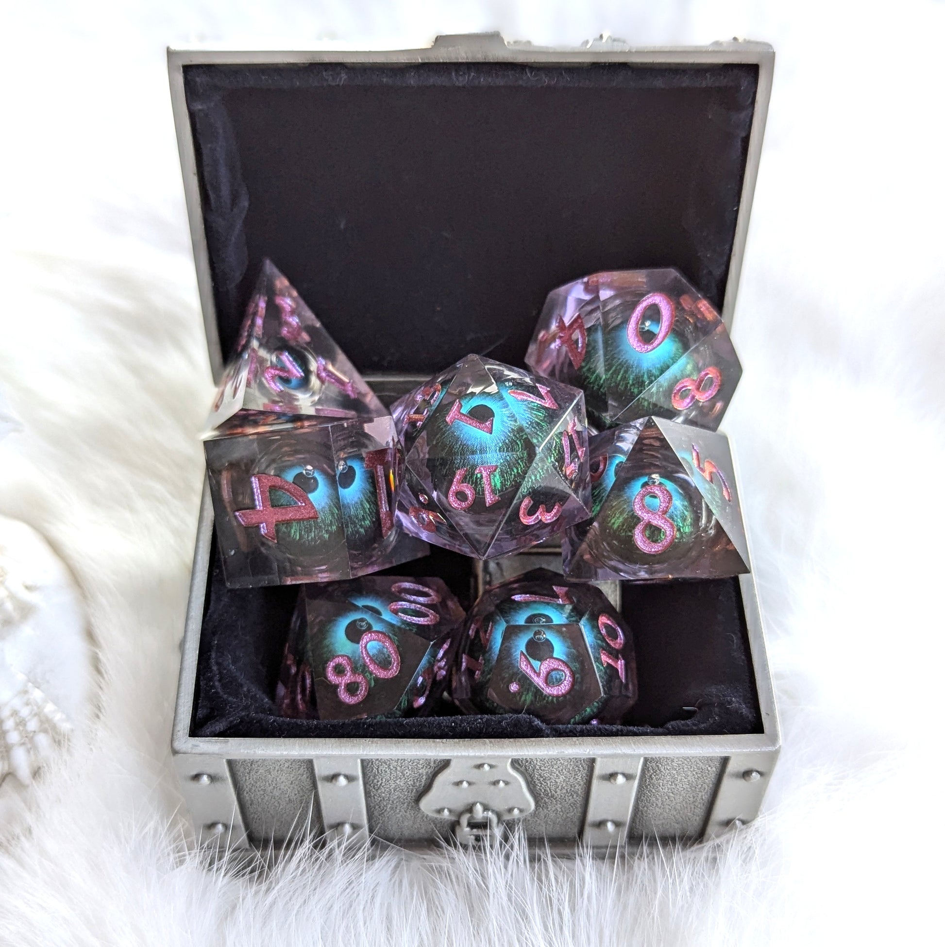 Mystic Eye Liquid Core Sharp Edge Dice Set with vibrant blue-green liquid core in purple resin, displayed in a silver box.