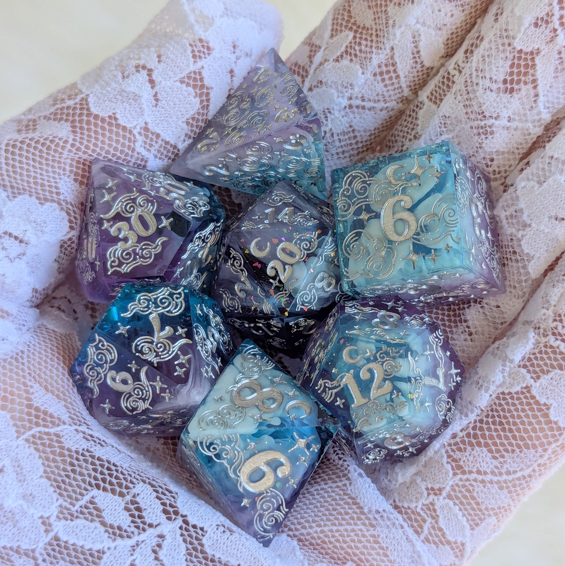 Dreamy Amethyst Sky sharp edge resin dice set held in a hand, featuring intricate engravings and cosmic colors.