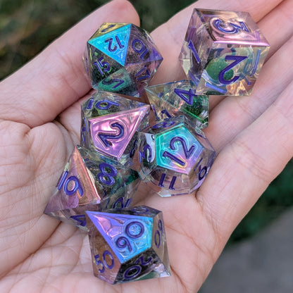 A set of iridescent polyhedral gaming dice held in a person's hand. The dice are transparent with a holographic rainbow sheen and dark printed numbers.