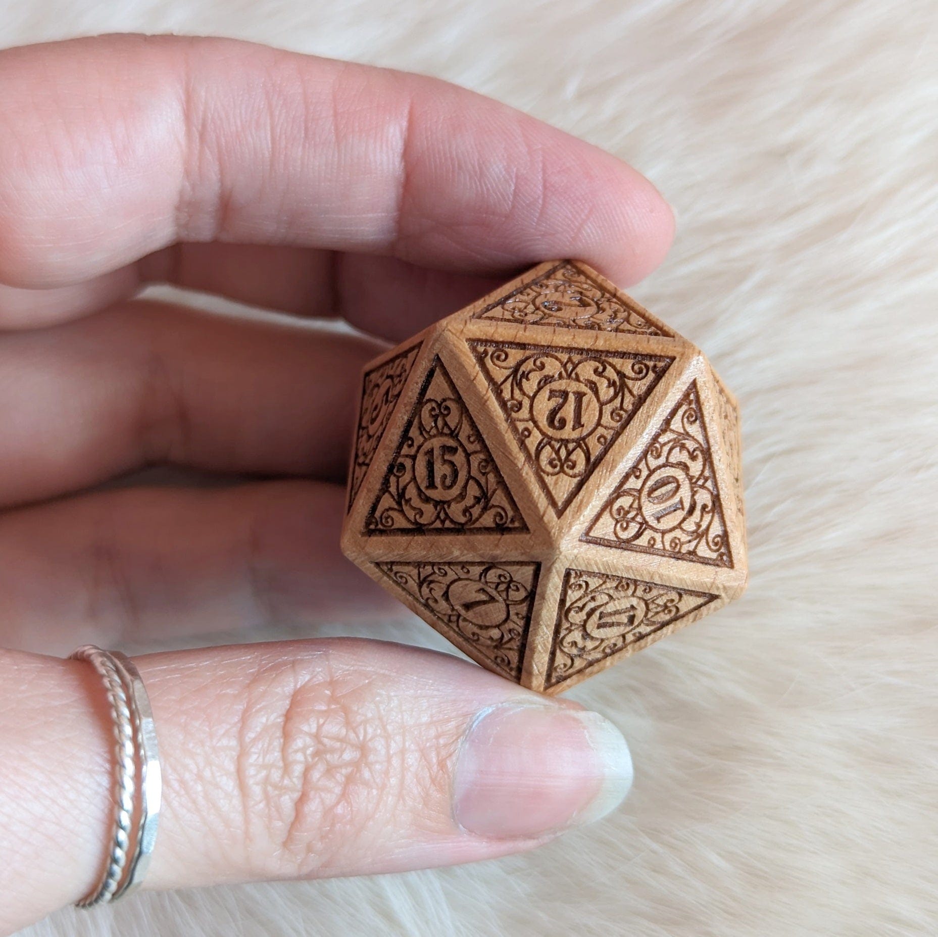 Intricate Garden Gate design wood D20 in hand with filigree art nouveau details, perfect for Dungeons and Dragons enthusiasts.