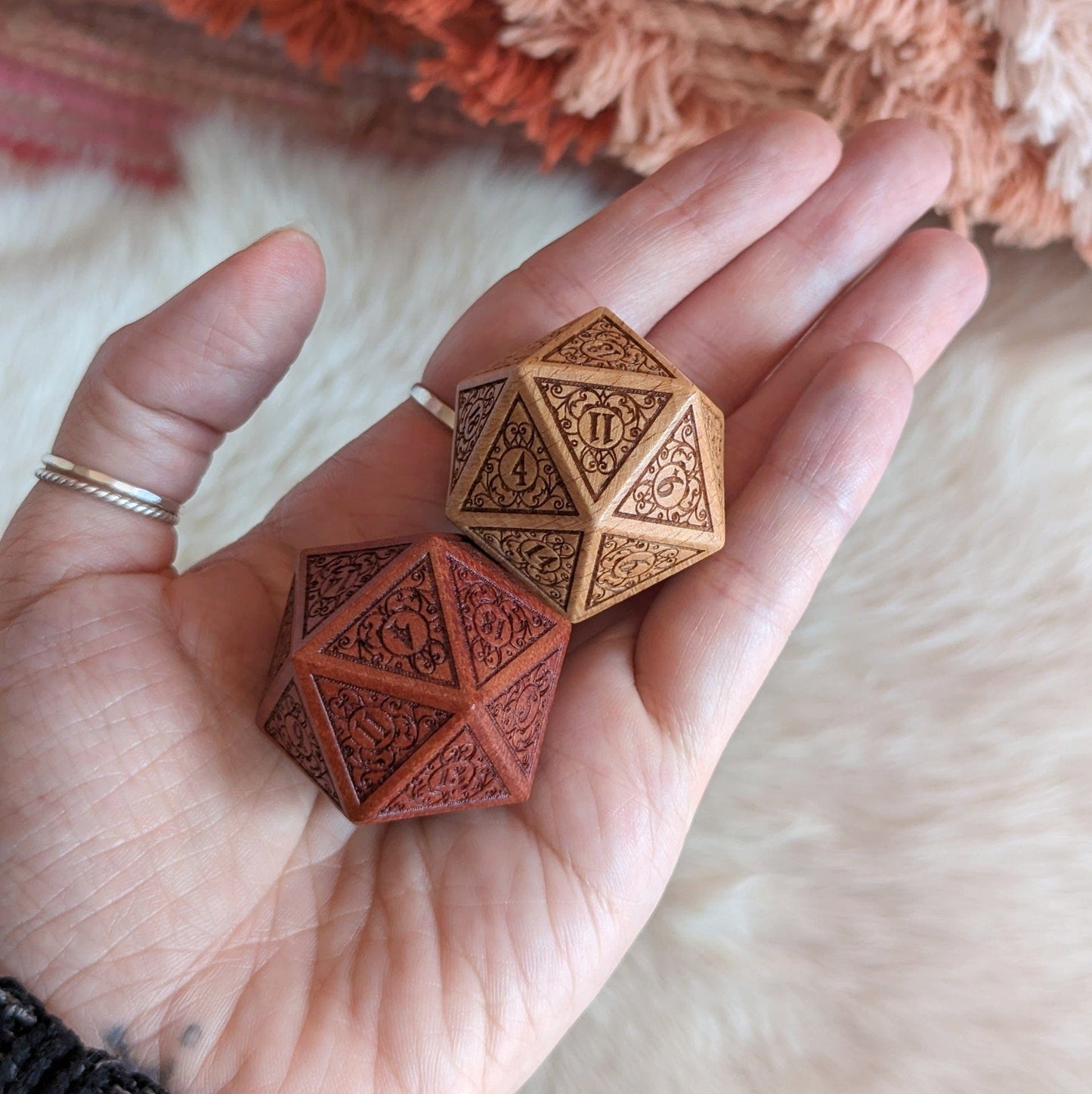 Hand holding intricately designed Garden Gate large wood D20 dice in beech and sandalwood with filigree art nouveau details.