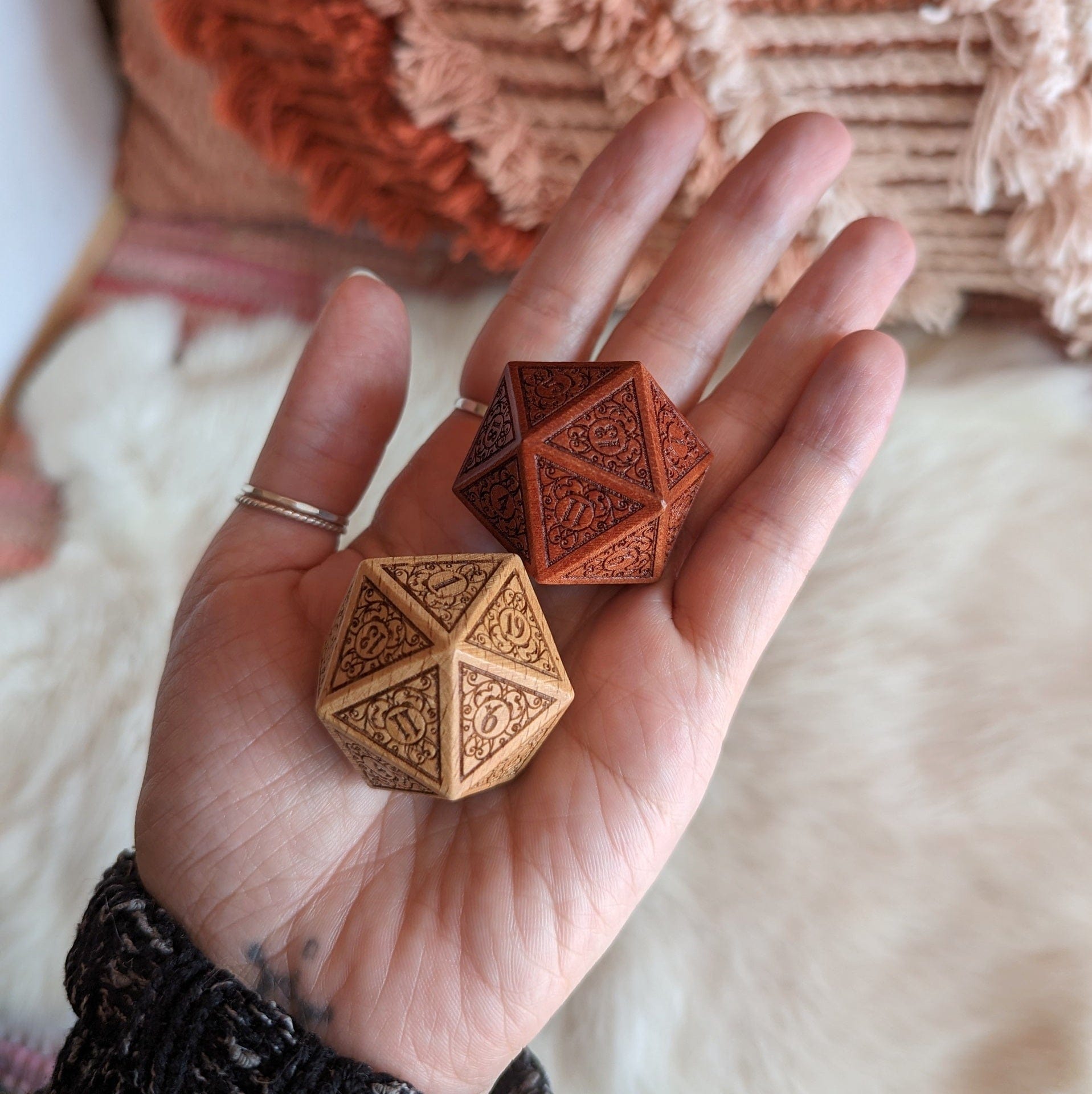 Hand holding intricate wooden D20 dice with filigree design in beech and sandalwood, perfect for Dungeons and Dragons gameplay.