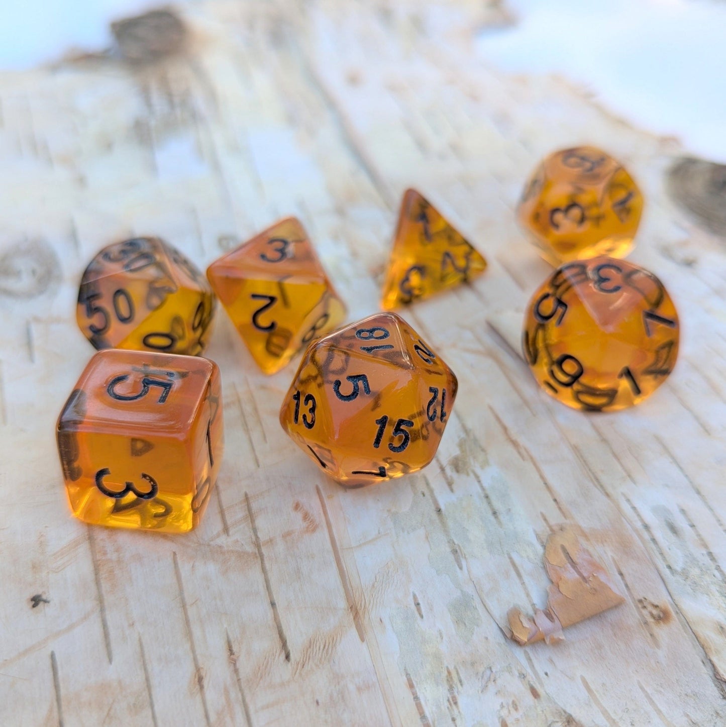 Amber Gems Dice Set with clear auburn-brown hue and black numerals on wood surface, perfect for tabletop RPGs like Dungeons & Dragons.