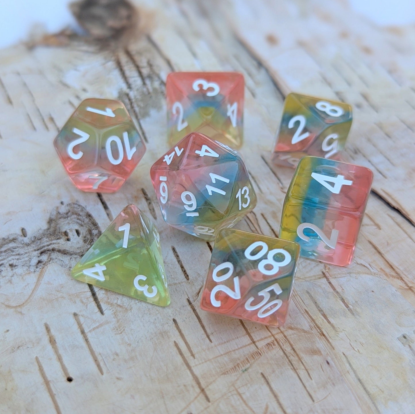 Aurora Sky Dice Set with rainbow layers of pink, blue, and yellow resin for tabletop RPGs like Dungeons & Dragons.