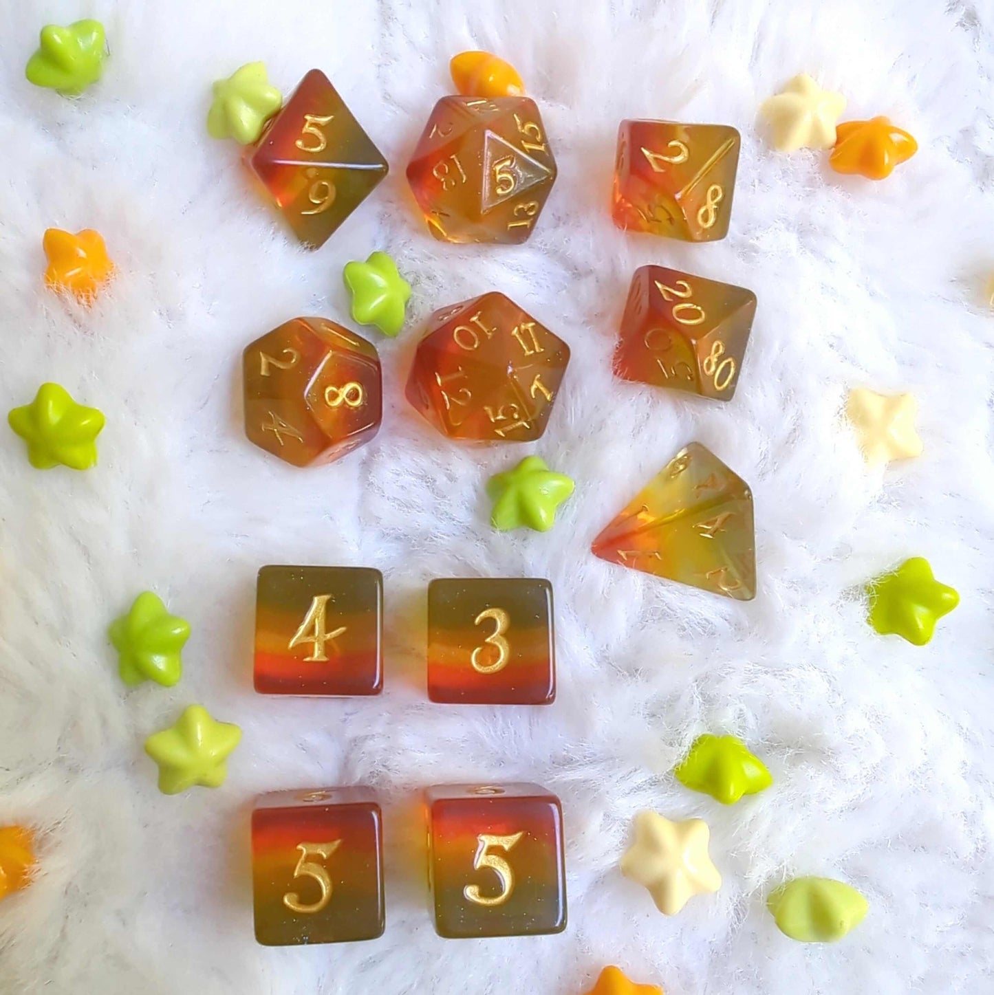 Autumn Sparkles Dice Set with glitter, showcasing fall colors in a 7 and 11 pcs set on a fluffy background surrounded by star-shaped beads.