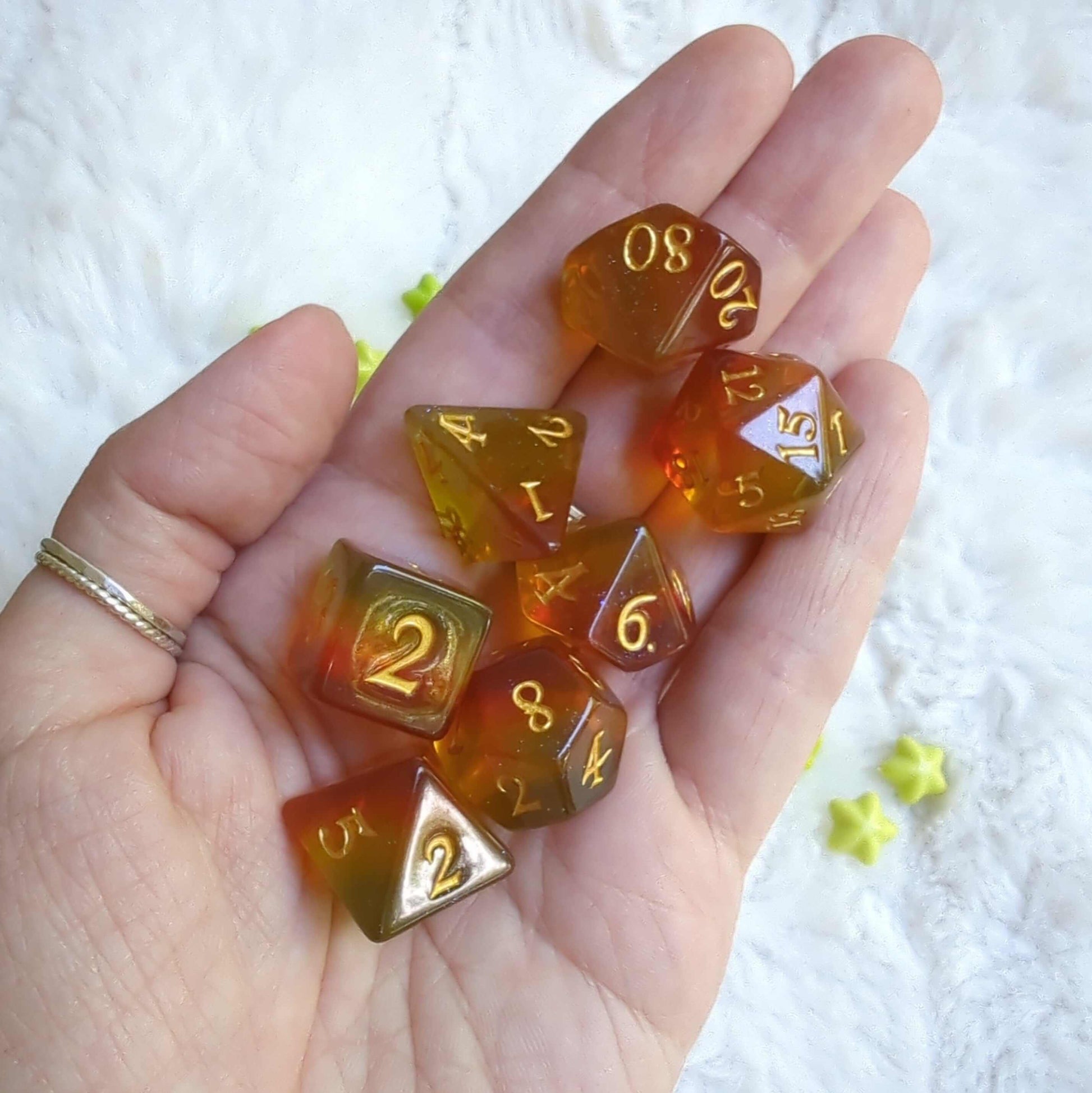 Hand holding Autumn Sparkles Dice Set with warm amber and gold hues, perfect for TTRPG gaming.