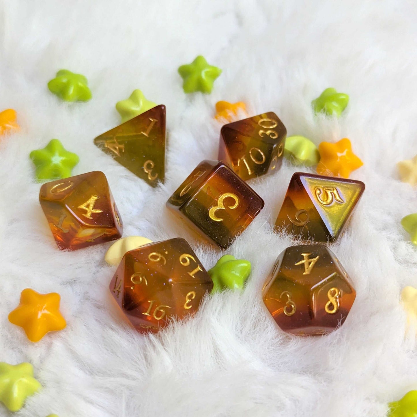 Autumn Sparkles Dice Set showcasing 7 polyhedral dice with shimmering autumn hues and glitter, surrounded by colorful star decor.