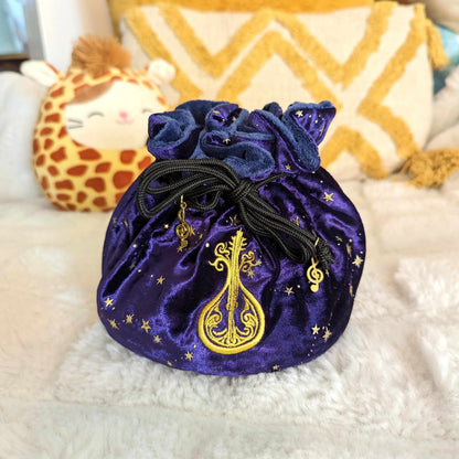 Purple bard dice bag with starry velvet, blue plush lining, embroidered lute design, and musical charm drawstrings.