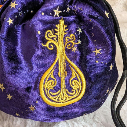 Bard dice bag in purple starry velvet with embroidered lute design and musical charm drawstrings, perfect for storing multiple dice sets.