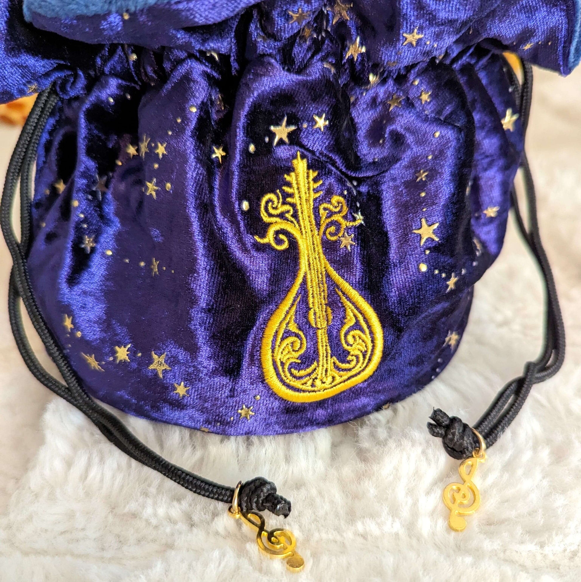 Purple velvet dice bag with enchanted lute embroidery, musical charms, and starry design, ideal for dice storage.