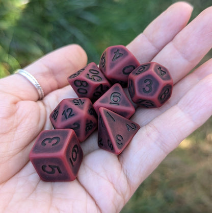 Hand holding matte red Blood DnD dice set for tabletop RPGs, including 7 polyhedral dice suitable for Dungeons and Dragons.