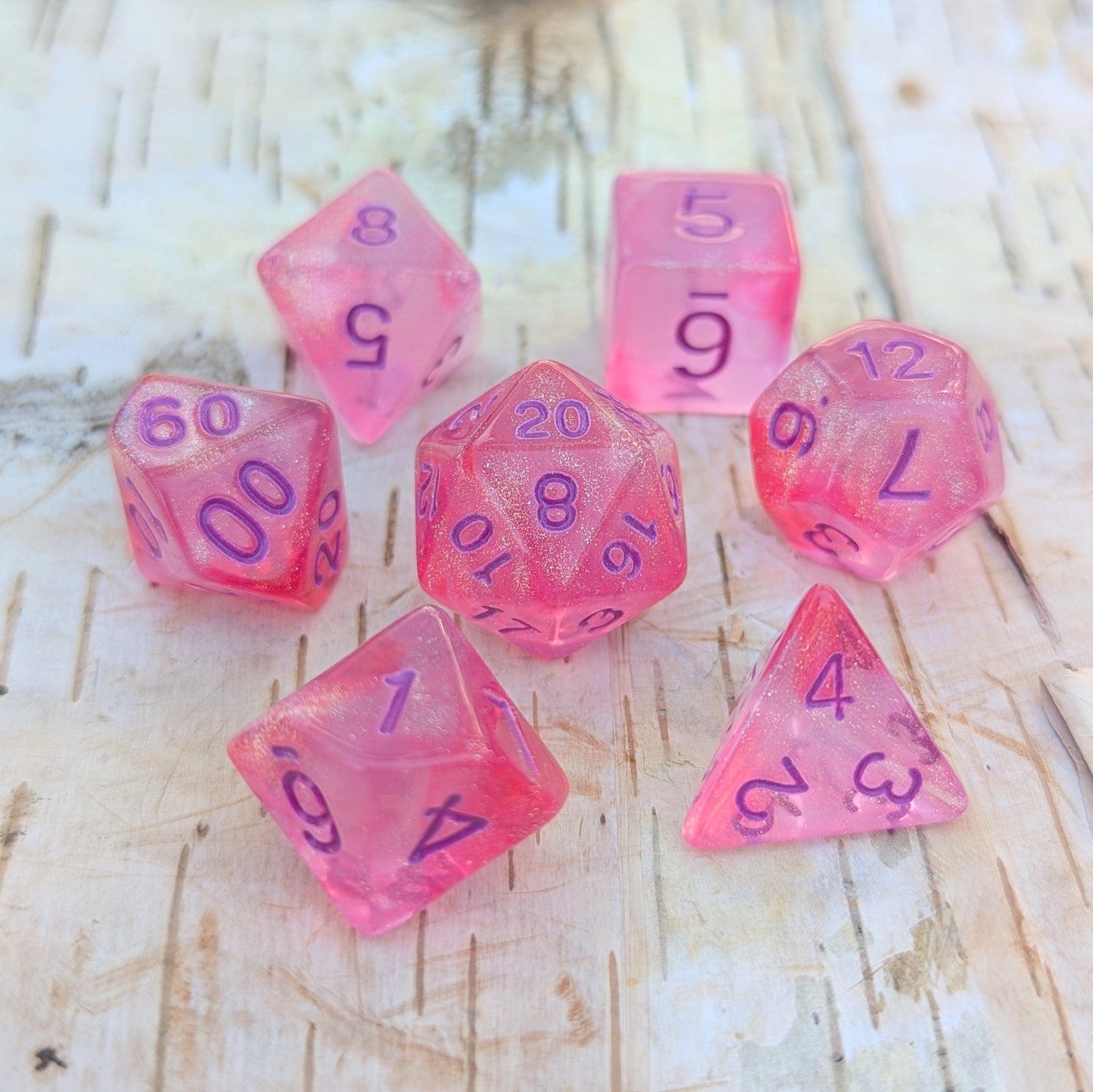 Cheshire Will O Wisp Dice Set in bright pink with purple numbers, 7-piece polyhedral dice for TTRPG like Dungeons and Dragons.