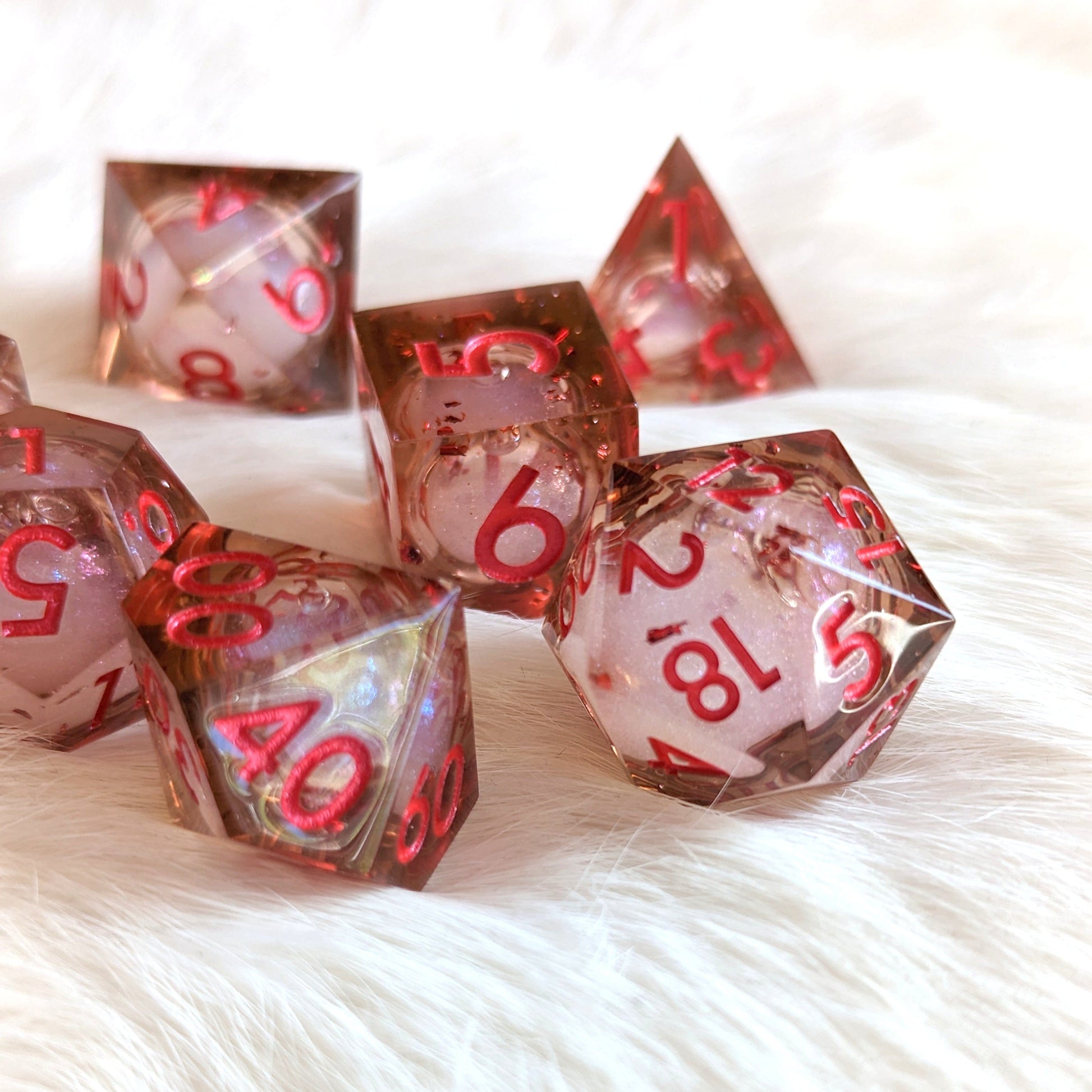 Crimson Liquid Core Sharp Edge Resin DnD Dice Set on white fur, featuring swirling micro shimmer inside, for tabletop role-playing games.