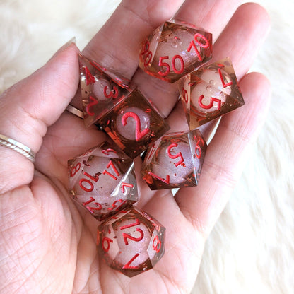 Hand holding Crimson Liquid Core Sharp Edge Resin DnD Dice Set with swirling shimmer for tabletop games.