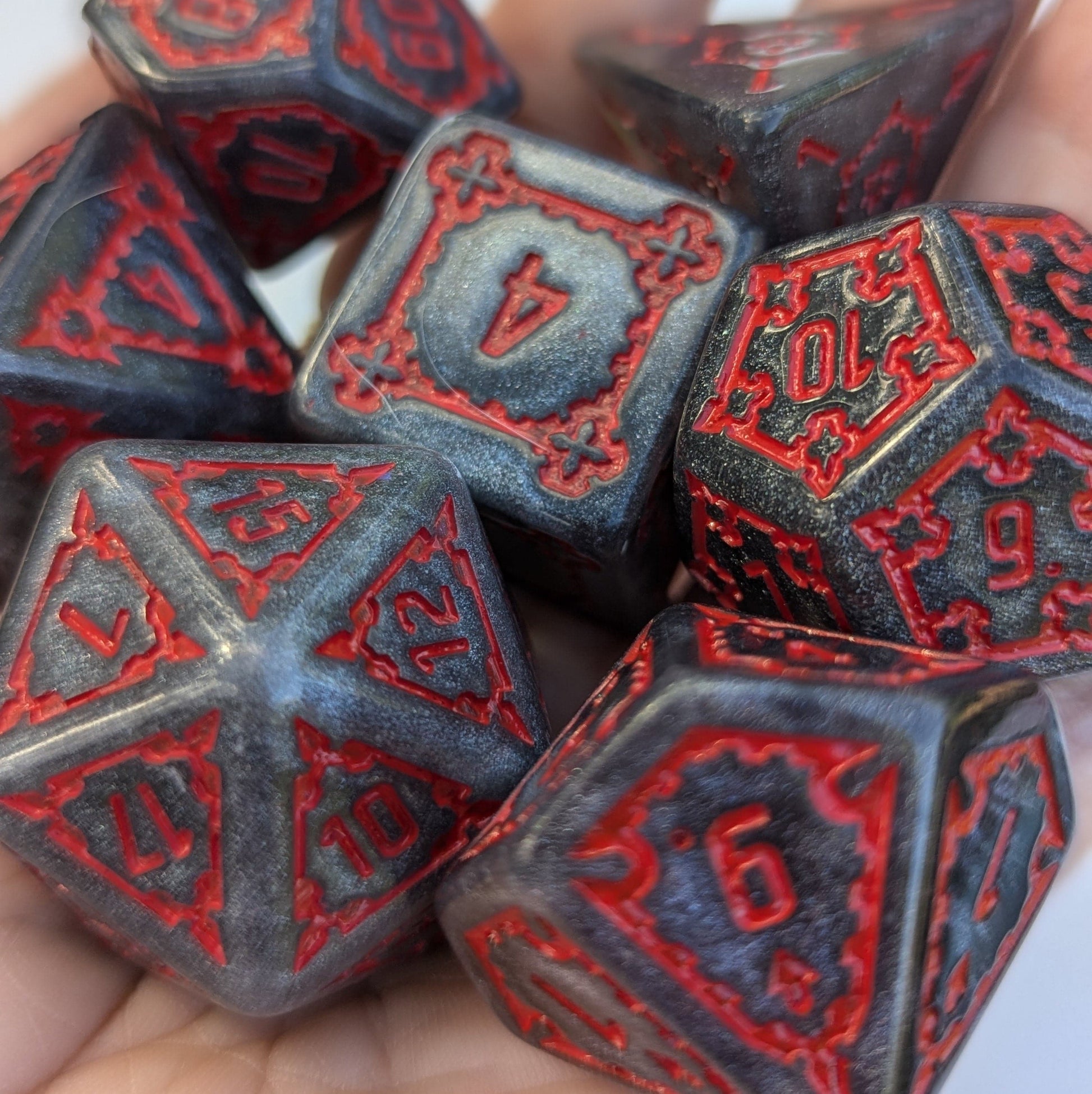 Extra large glittering dark grey dice set with red numbers, 25mm 7-piece Dark Castle Dice in hand.