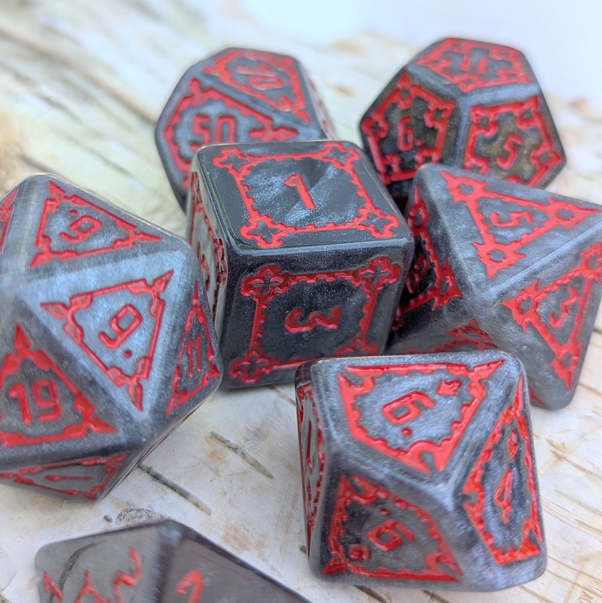 Dark Castle Dice set with large glittering grey dice and red numbers, 25mm, extra large 7-piece set on a wooden background.