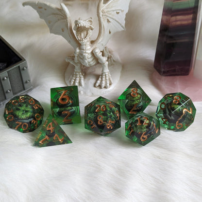 Dark green liquid core DnD dice set with moving eye design on white fur background, featuring a dragon figurine.