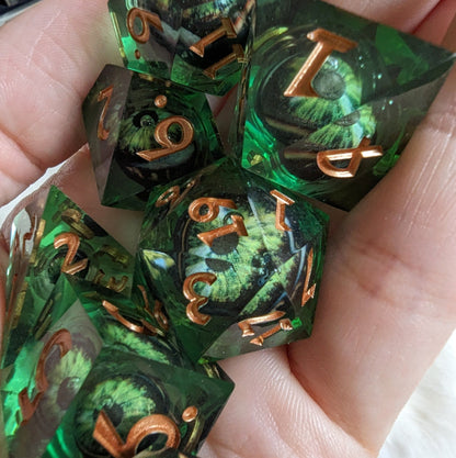 Dark green moving eye liquid core sharp edge DnD dice set in hand, showing intricate design for tabletop role-playing games.