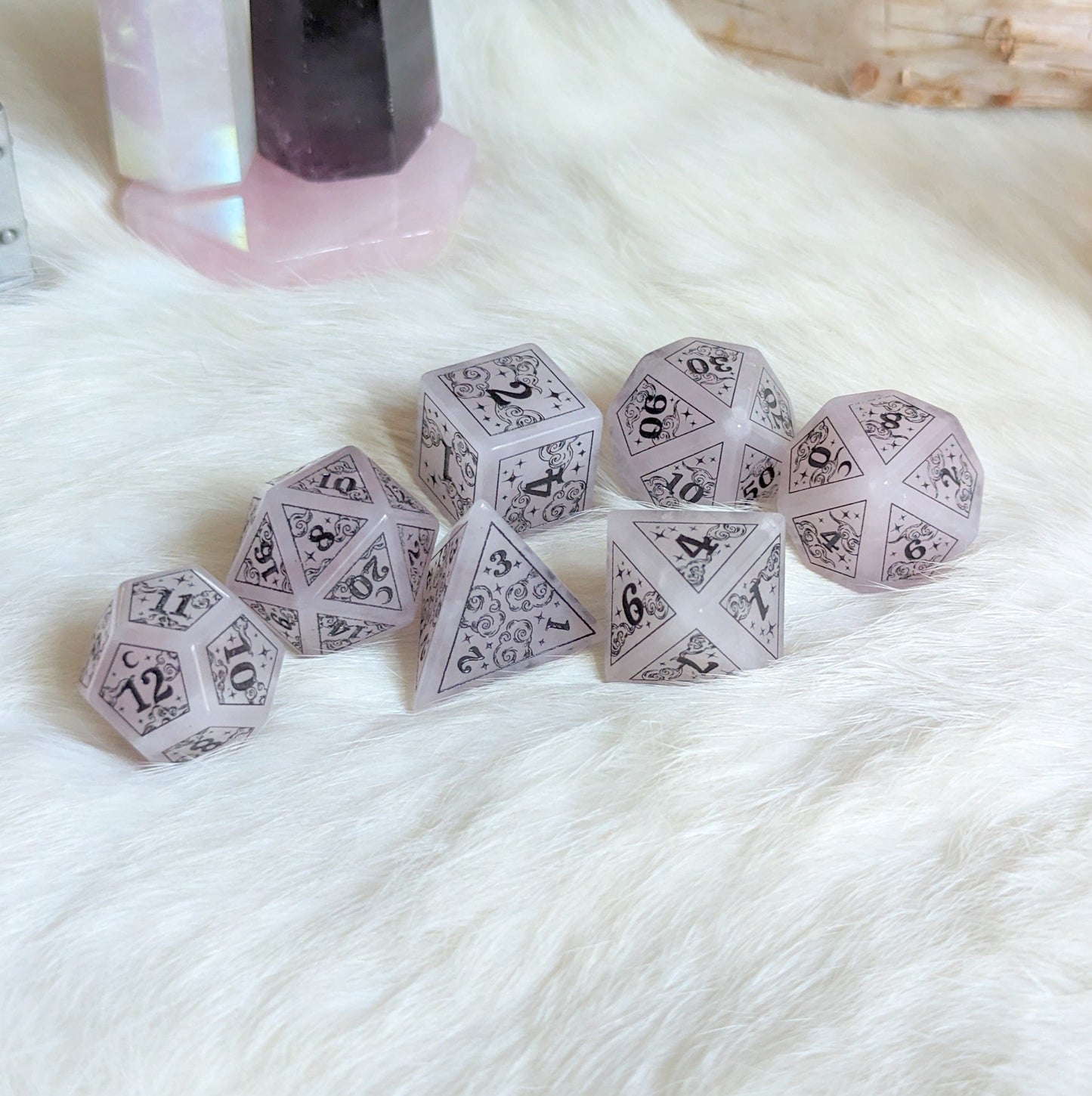 Dreamy Rose Quartz Dice Set with clouds, moons, and stars design on white fur, perfect for Dungeons & Dragons games.