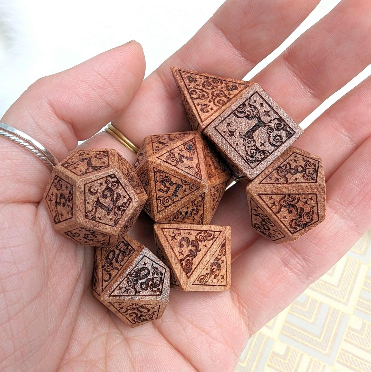 Hand holding Dreamy Star and Moon Wood Dice Set for Dungeons & Dragons, showcasing intricate designs of clouds, stars, and moons.