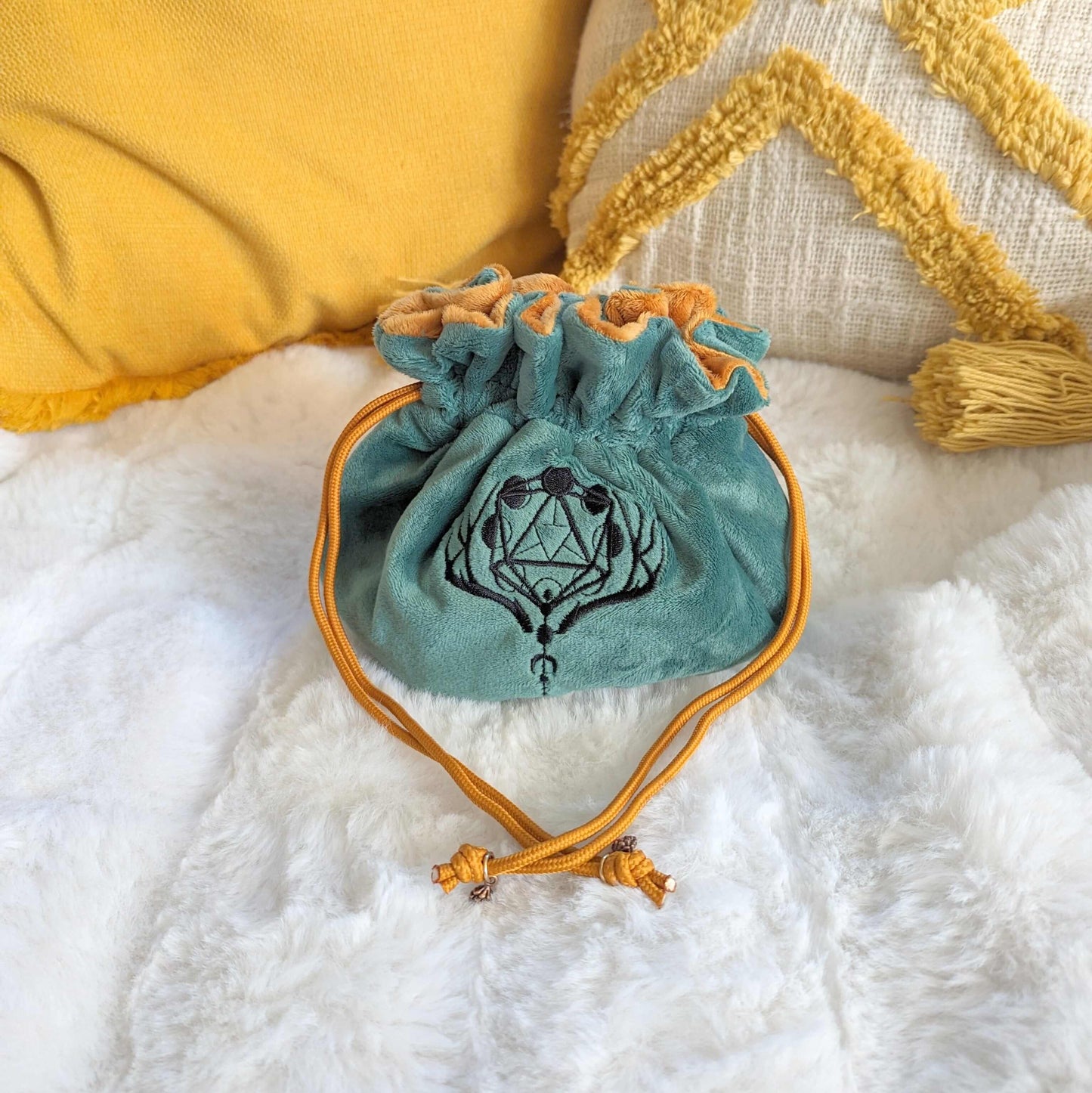 Green and auburn plush druid dice bag with D20 moon phase embroidery and pinecone bead drawstrings displayed on a white fluffy background.