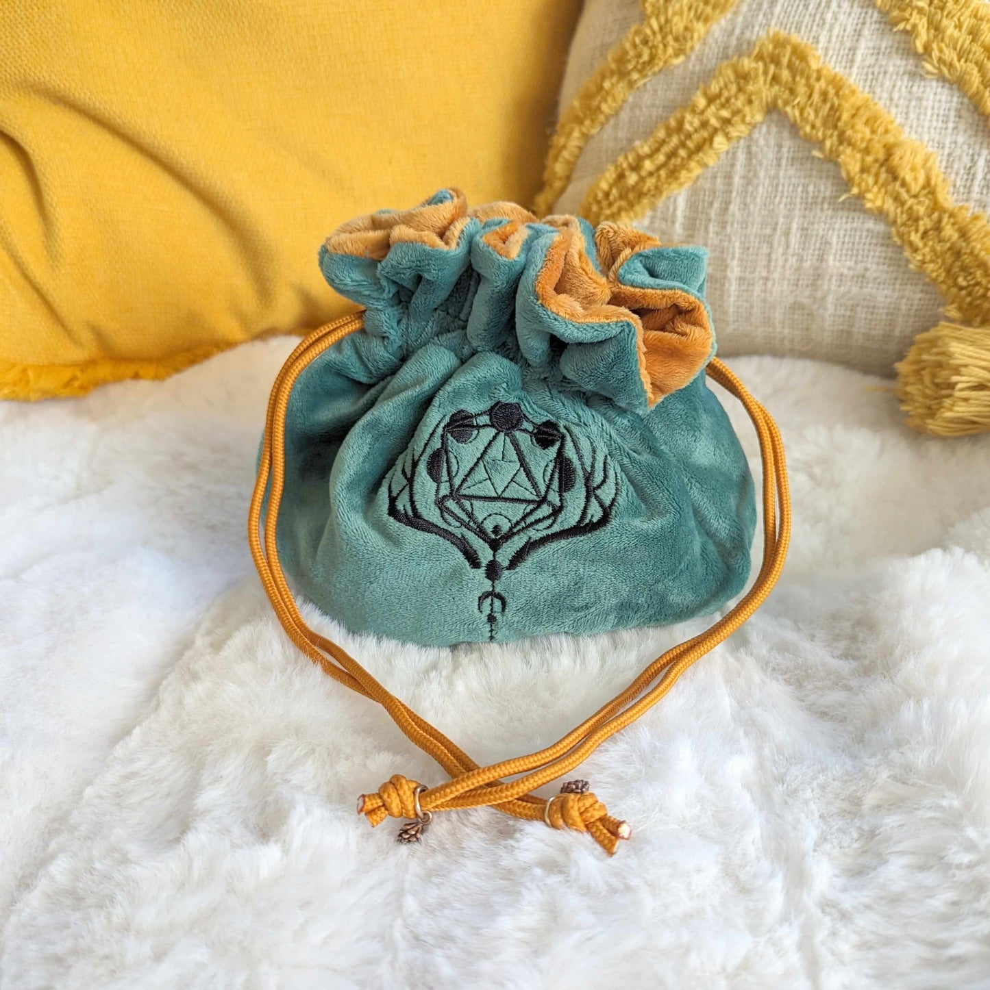 Green and brown druid dice bag with D20 moon phase embroidery, antler design, and pinecone bead drawstrings on a cozy surface.