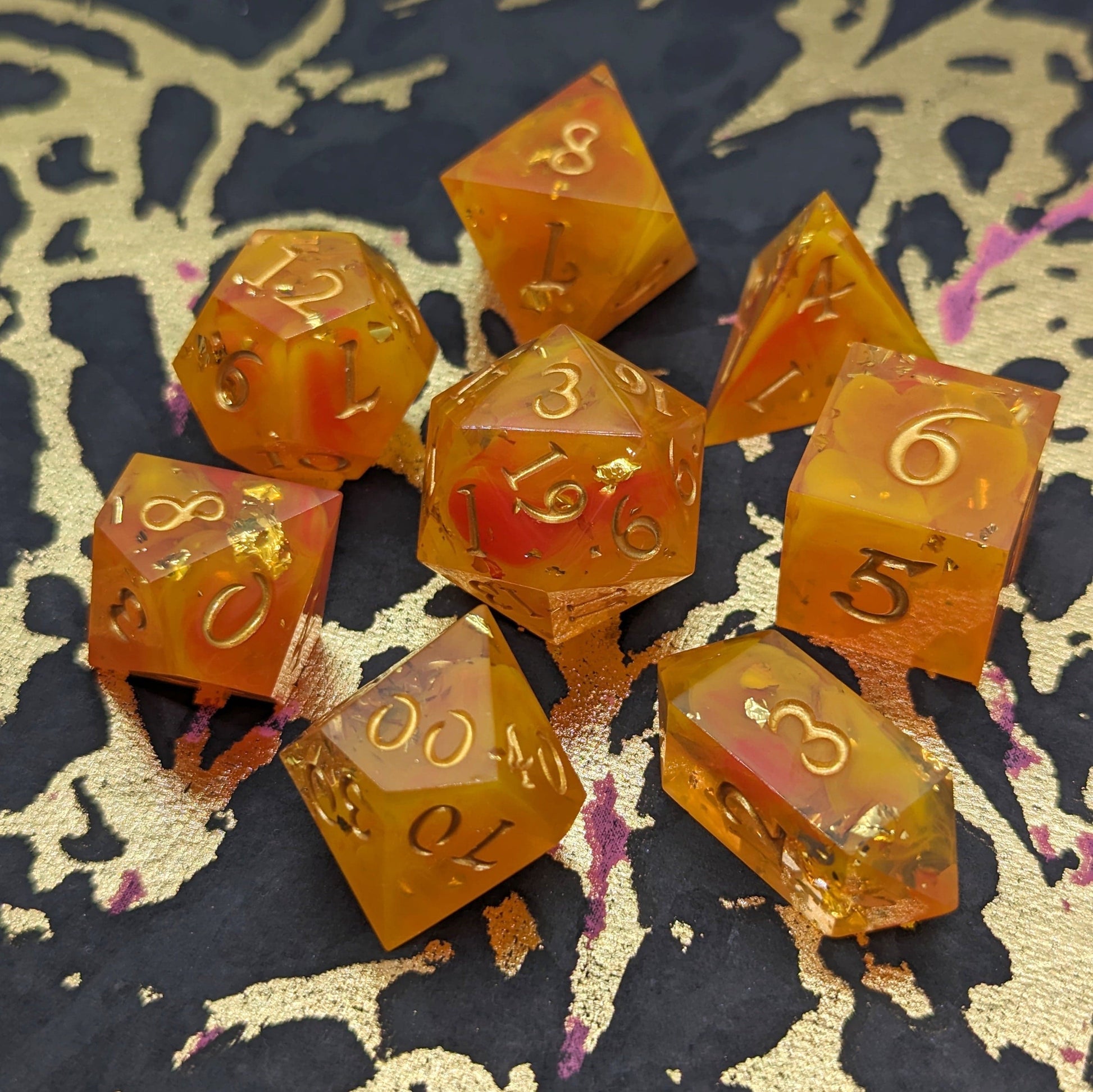 Flame Cast DnD Dice Set with vibrant orange, yellow, and red swirls, gold font, hand-poured for a unique TTRPG experience.