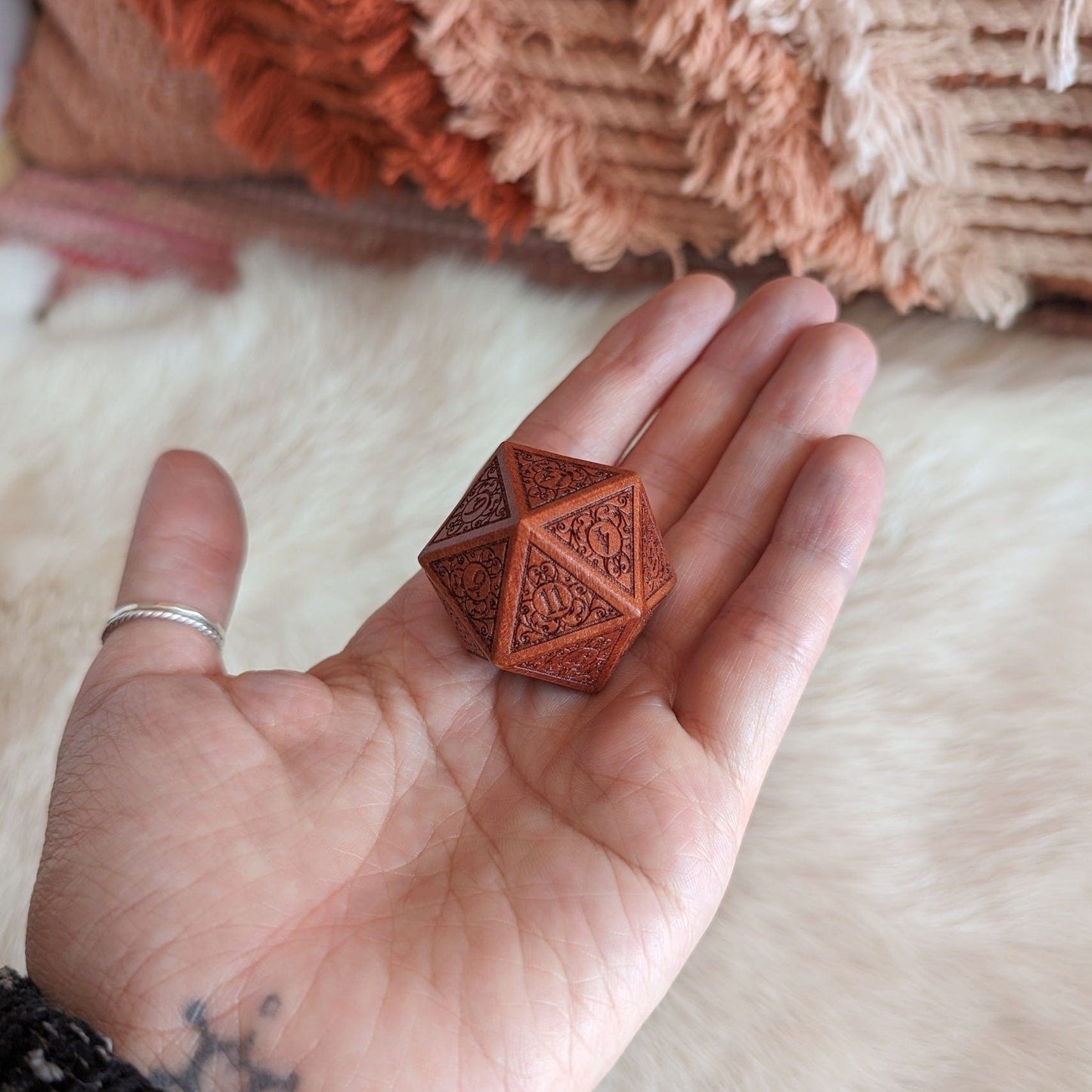 Hand holding a intricately designed wood D20 die, featuring filigree art nouveau details, ideal for Dungeon and Dragons enthusiasts.