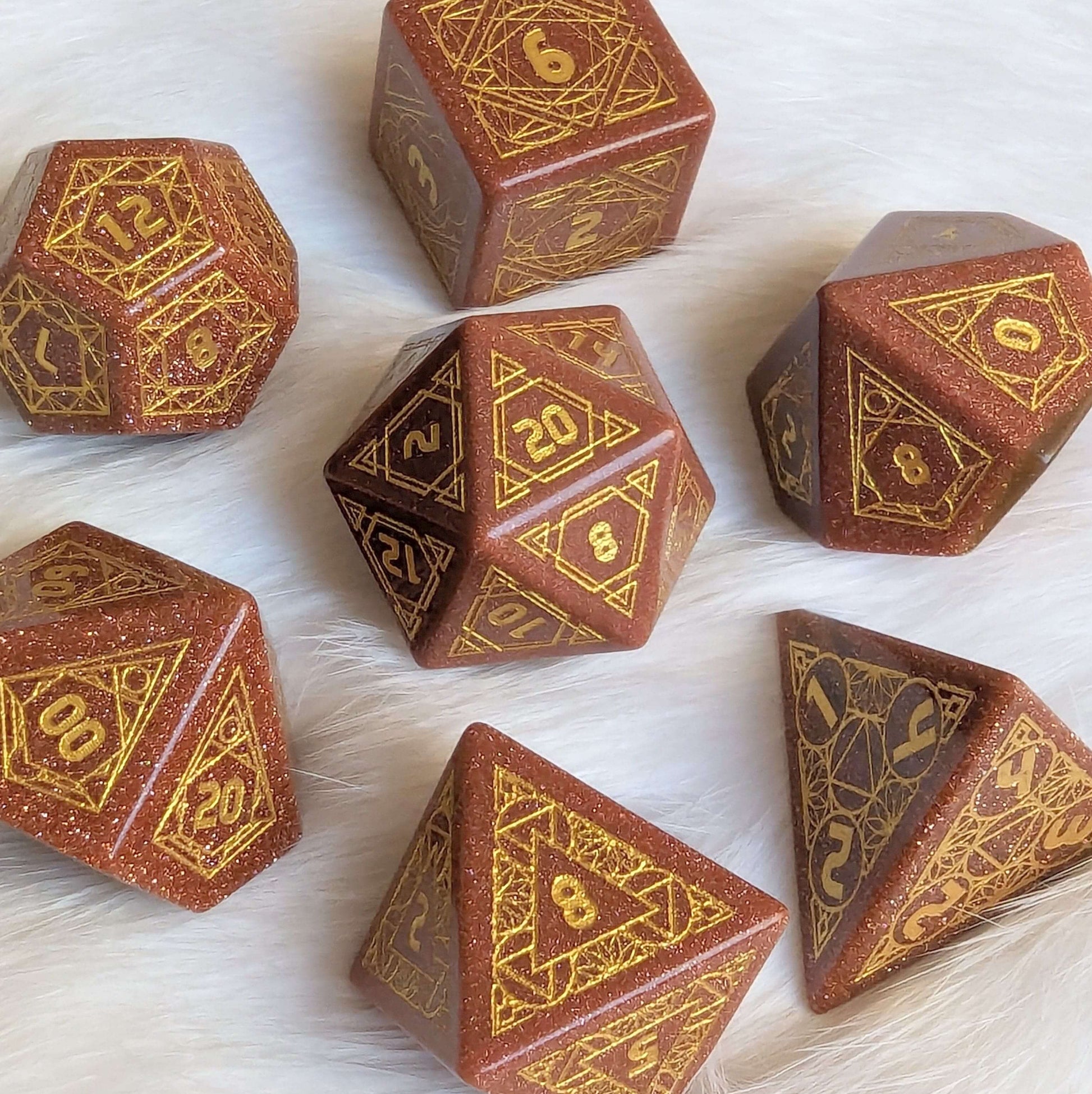 Geometric Goldstone Dice Set, 7-piece carved gemstone TTRPG dice on a white surface, ideal for fantasy tabletop role-playing games.