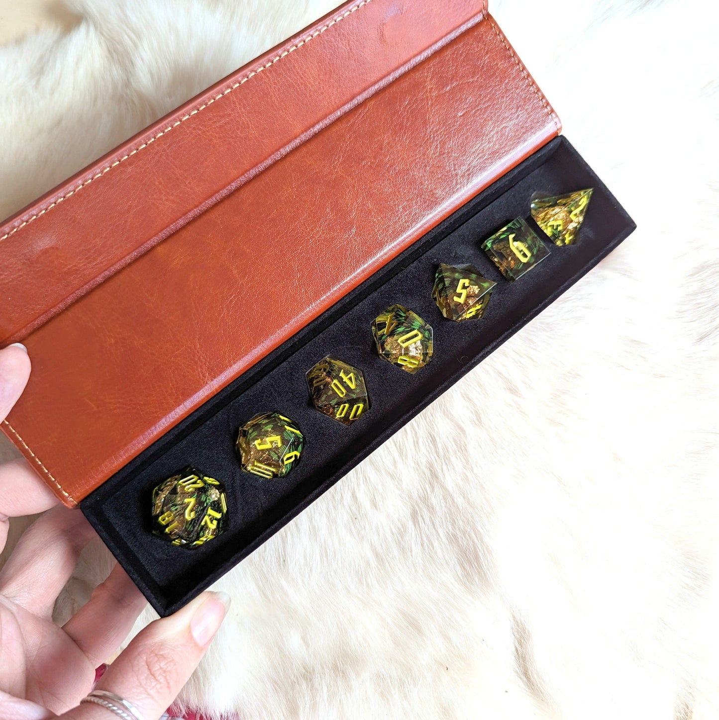 Green Feather Sharp Edge Resin DnD Dice Set with gold foil and fantasy font in leather box, ideal for tabletop role-playing games.