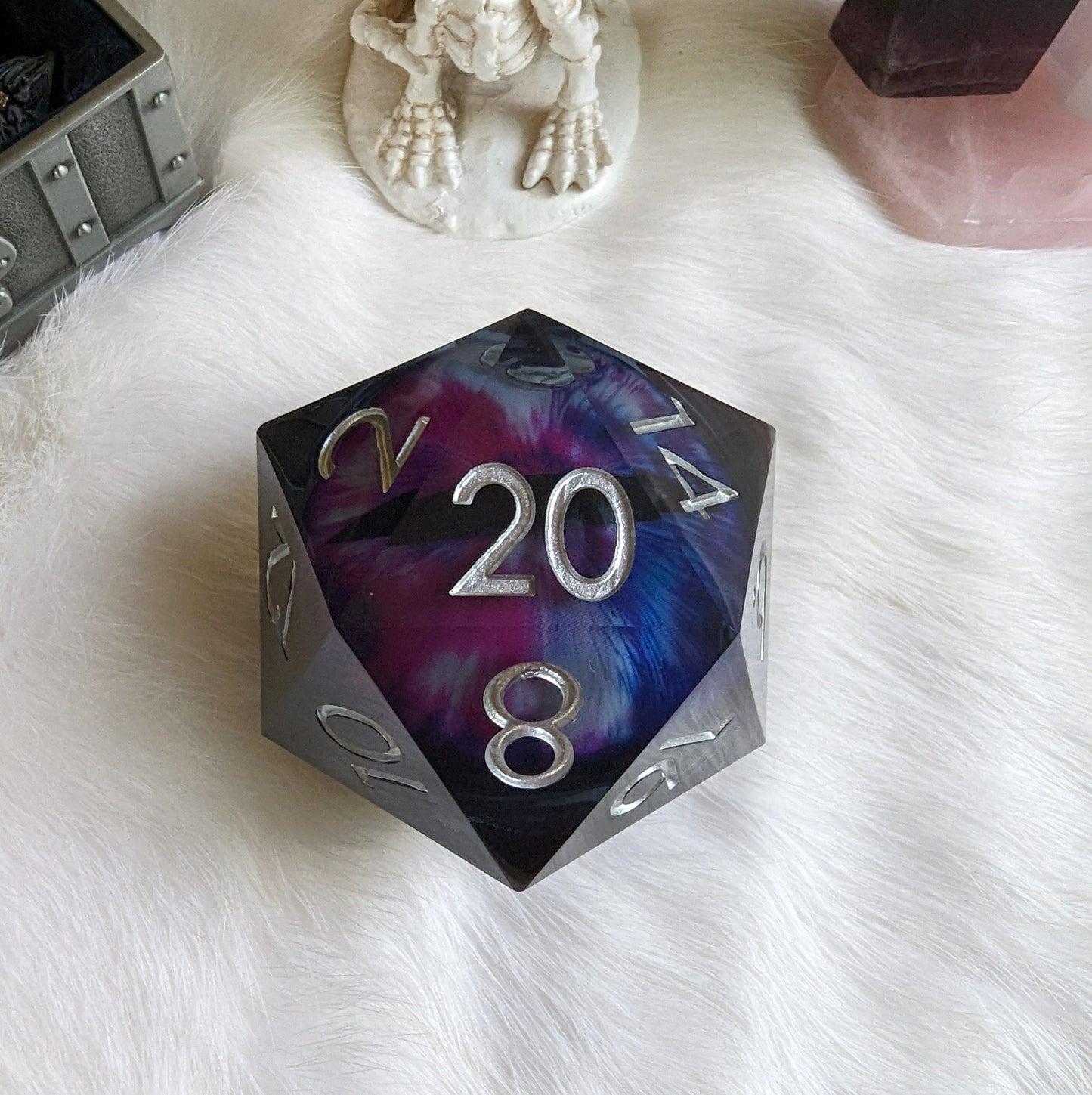 Large liquid core eye D20 dice with swirling glitter for tabletop games like Dungeons and Dragons, on a white fur background.