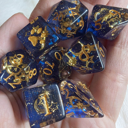 Hand holding Moon and Stars Dice Set with gold glitter, celestial design, and paw print on extra D6 for Dungeons and Dragons.