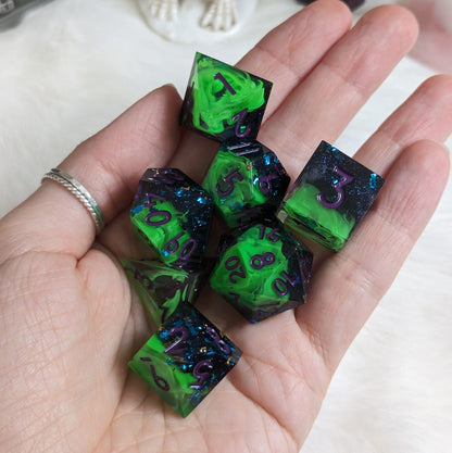 Hand holding a 7-piece neon green and black DnD dice set with sharp edges and purple numbers, perfect for tabletop role-playing games.