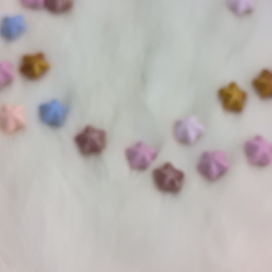 A set of translucent purple polyhedral gaming dice with gold numbering and iridescent glitter, being shook in a hand so you can see the liquid moving on the inside