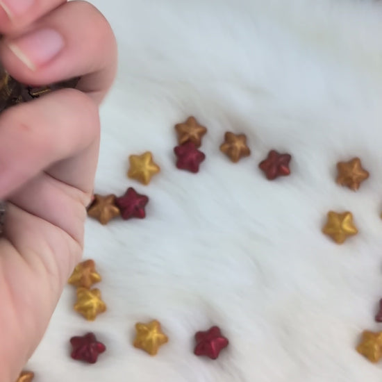 A set of transparent acrylic polyhedral dice with gold-colored numbers and pink cherry blossom floral designs show in a video being held be a hand moving around the dice to show off the different angles