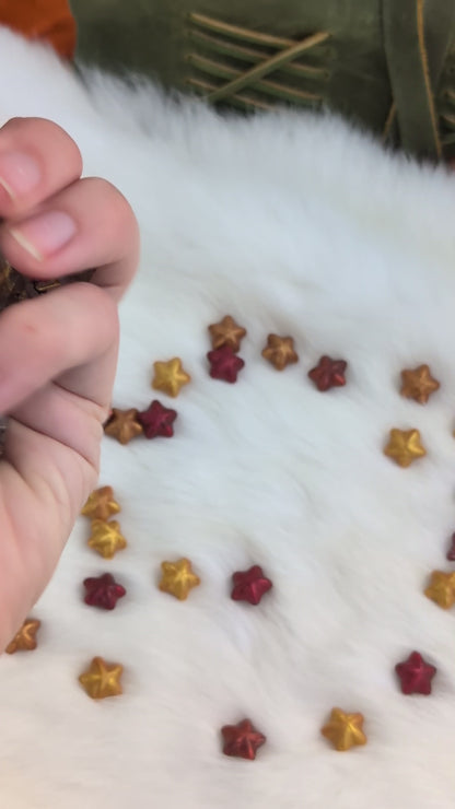A set of transparent acrylic polyhedral dice with gold-colored numbers and pink cherry blossom floral designs show in a video being held be a hand moving around the dice to show off the different angles