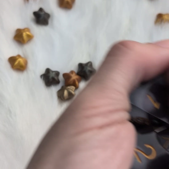 A set of translucent smoky gray polyhedral gaming dice with metallic gold numbers being shook in a hand to display the liquid moving on the inside