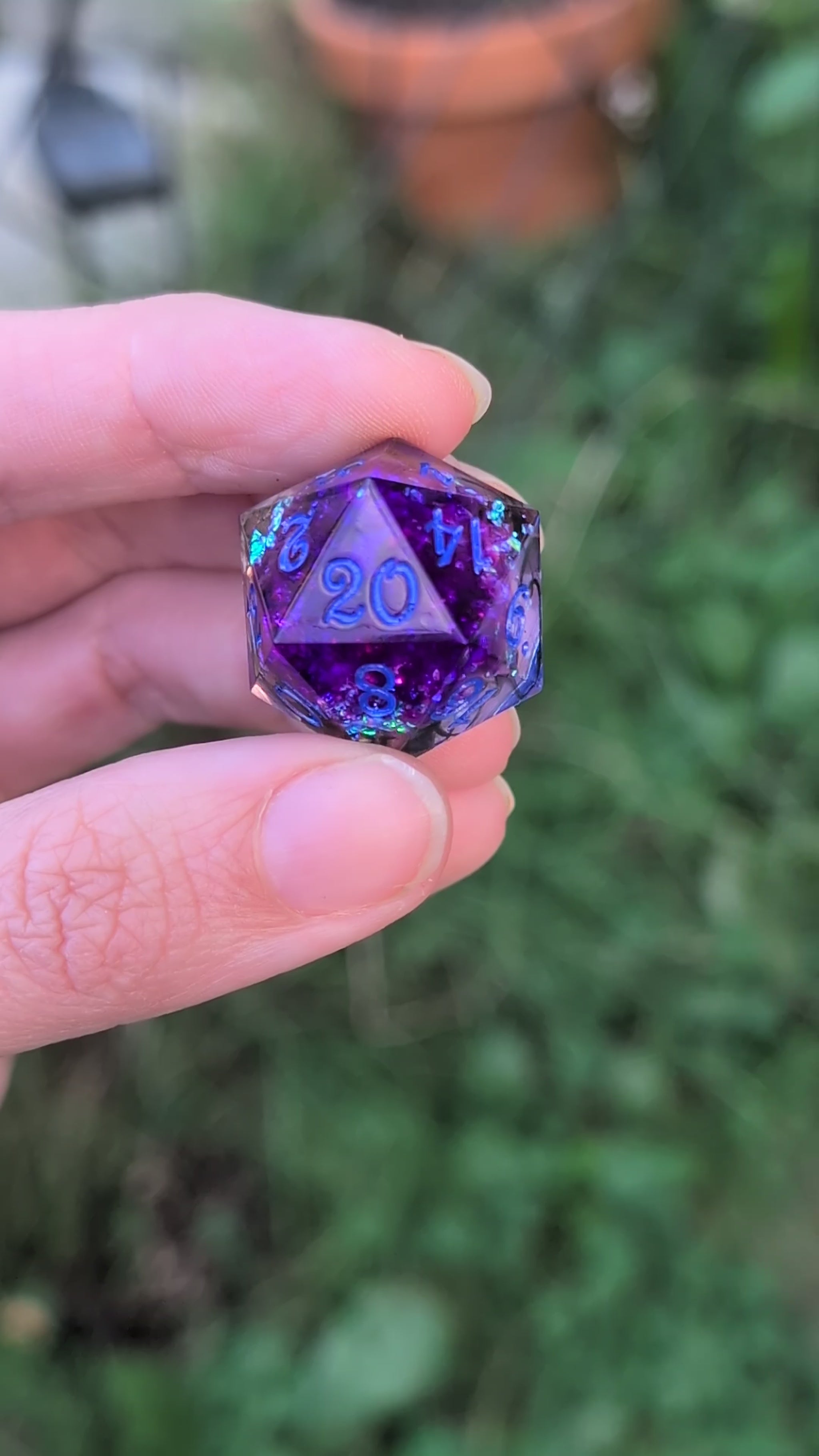  blue and purple holographic polyhedral dice and star-shaped dice being held in a hand moved around in a video to how the different angles of the dice